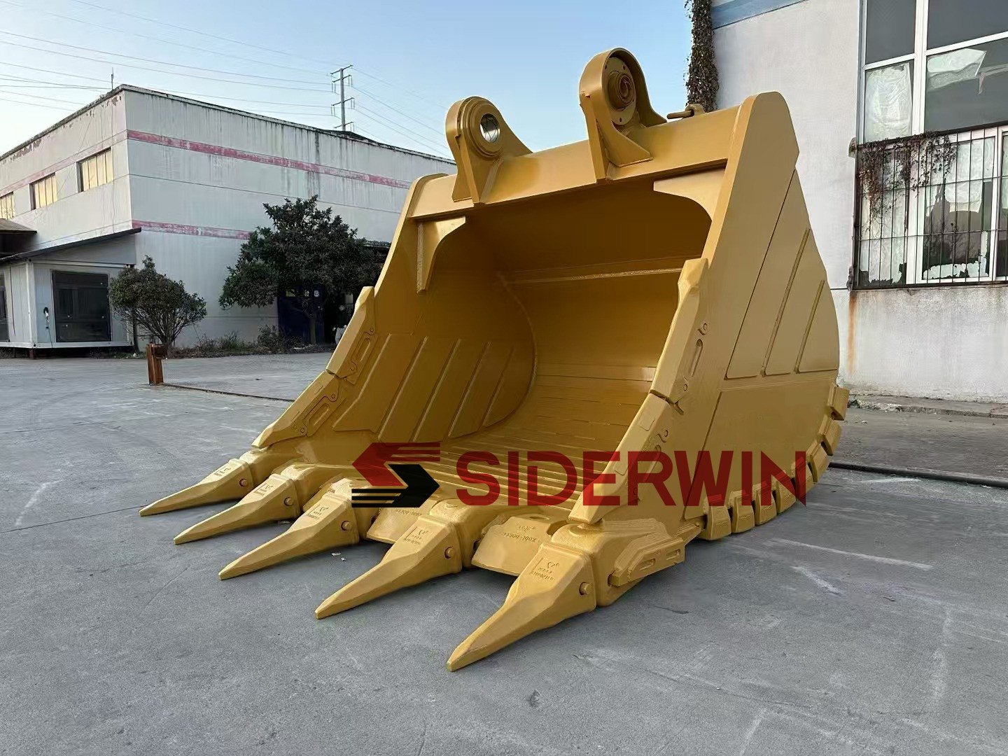 Front view of a yellow excavator bucket with mounting bores above the shell