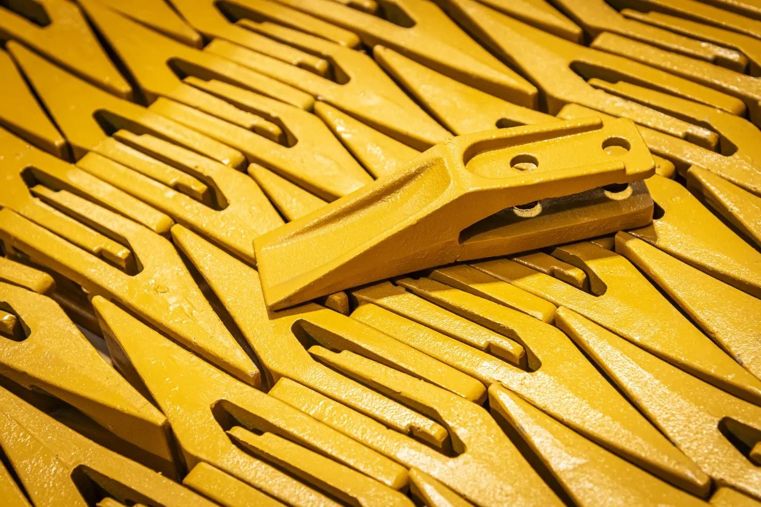 Close-up of yellow bucket teeth showing pockets and pin holes
