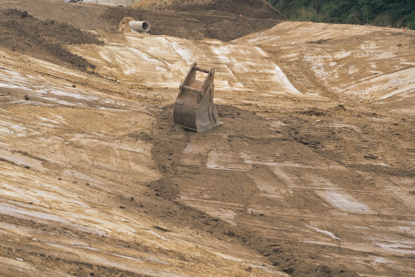 Detached excavator bucket standing on a prepared construction site
