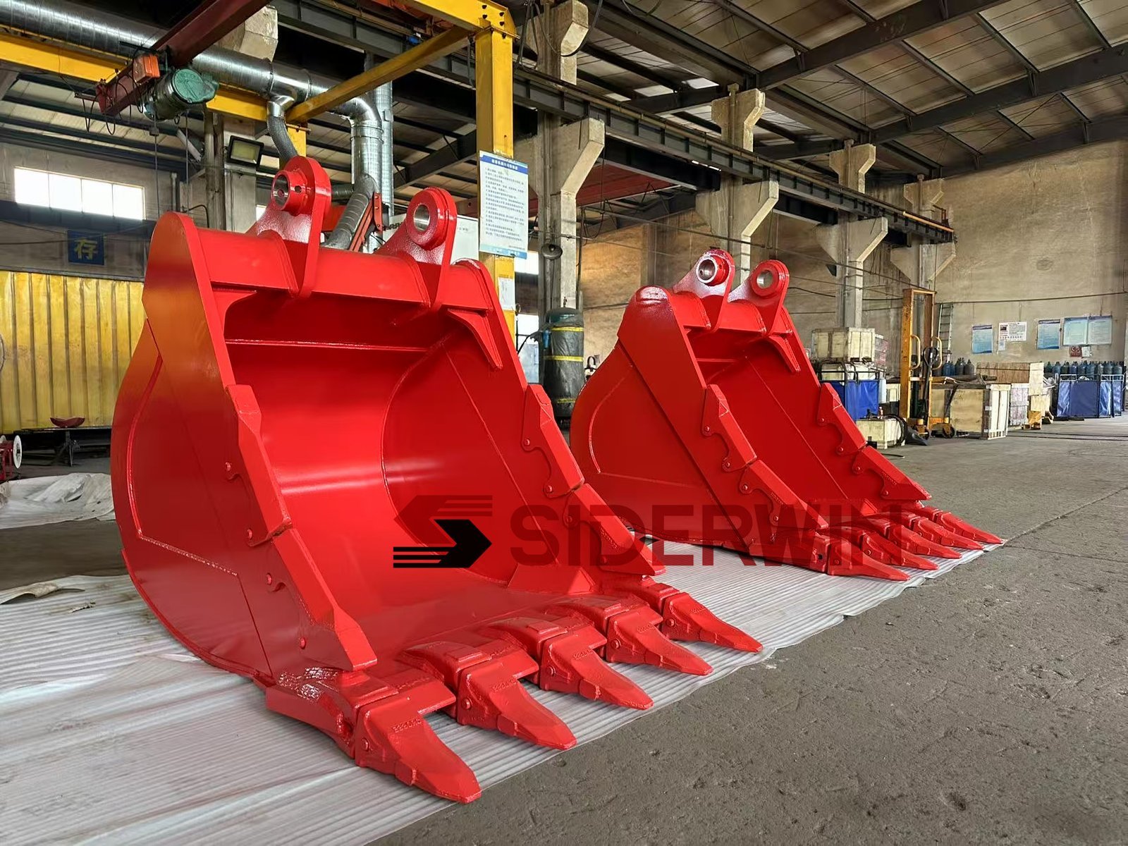 Two red excavator buckets showing mounting ears and cutting teeth